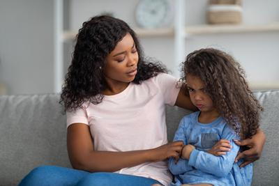 Angry-Child-with-Her-Mom-Sitting-on-the-Sofa